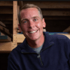a man smiling and wearing a blue sweater