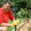 man wearing a red shirt in a garden planting a flower