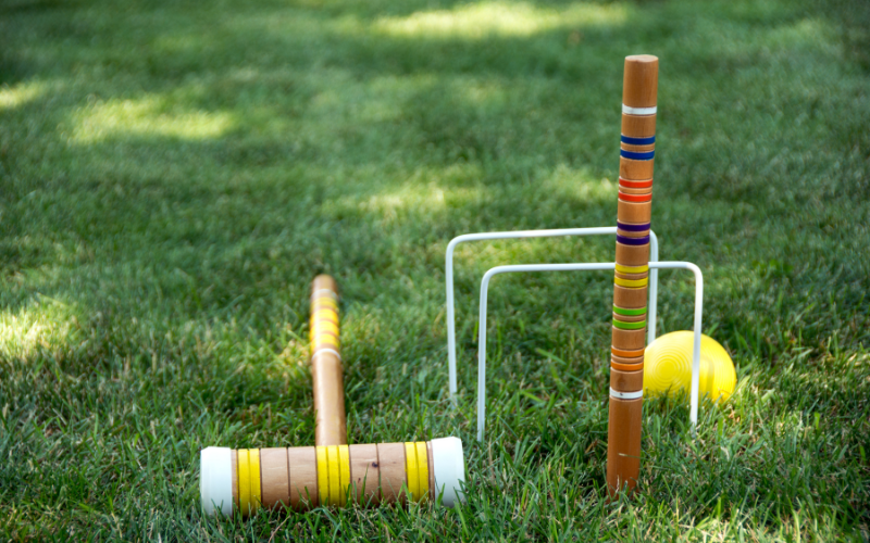 Croquet set with bright yellow ball and mallet in backyard