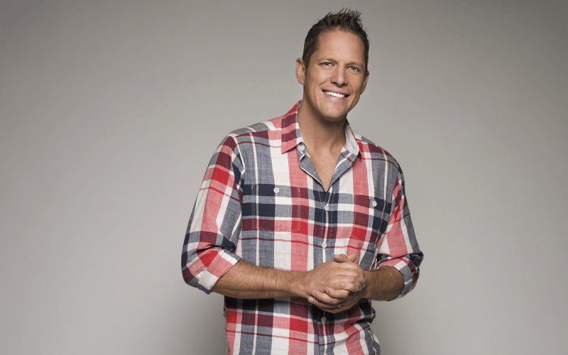 Chris Lambton wearing red, black and white plaid shirt smiling at camera headshot