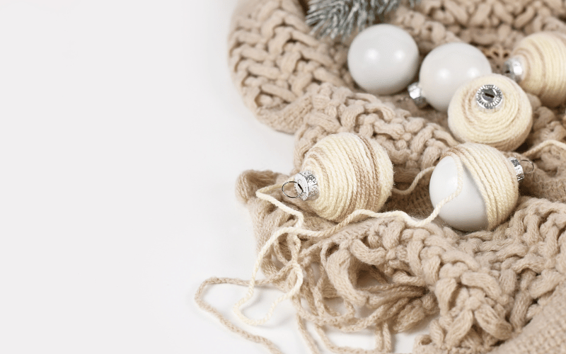 Close up of handmade knit beige shawl with knitted holiday handmade bulbs