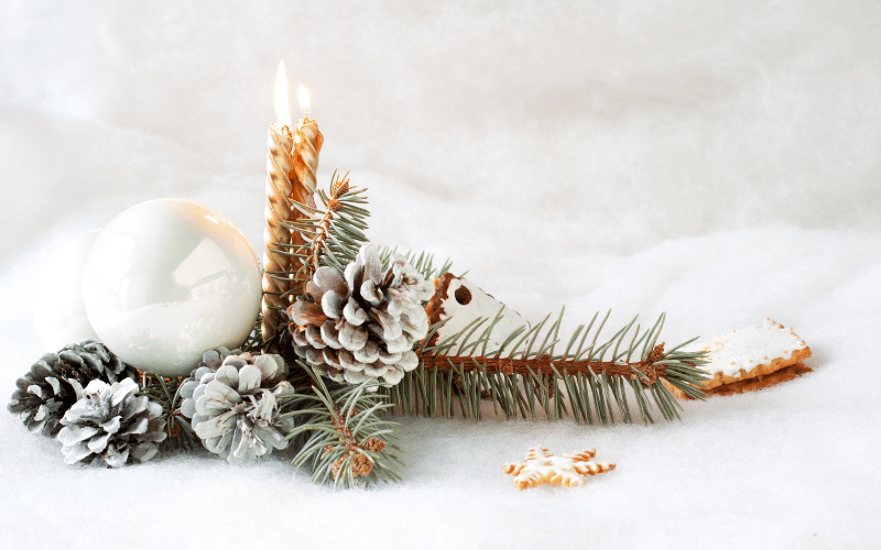 Decorative pine tree branches with white shiny bulb and pinecones over white fake snow 