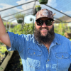 Destin Noak Texas Garden Guy Smiling Blue Jean Shirt In GreenHouse