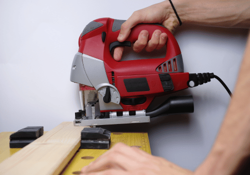 Person using red jigsaw to cut wood