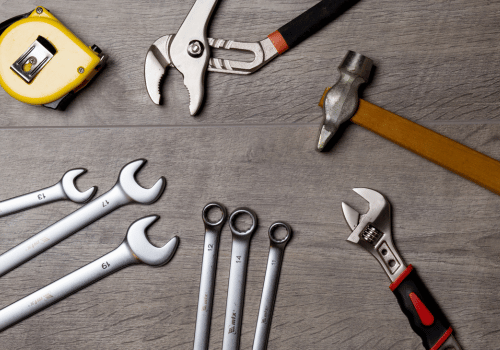 Tape measure, wrench, hammer and socket wrenches over dark hardwood floor background