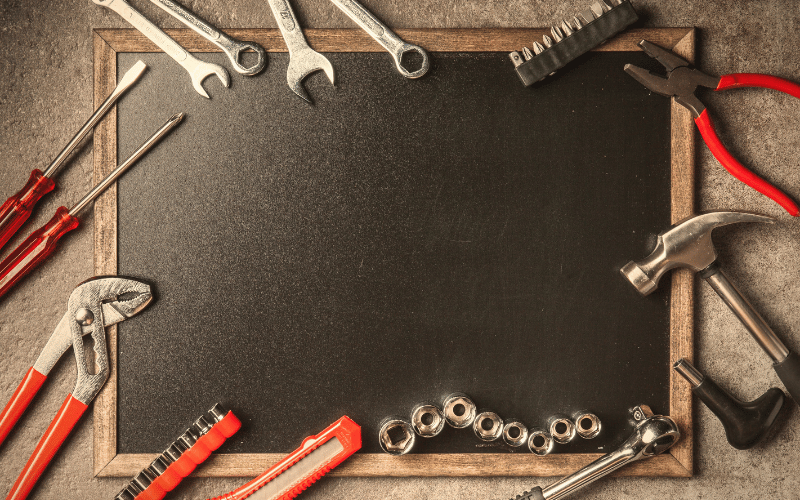 Black board covered in assortment of DIY red and silver tools