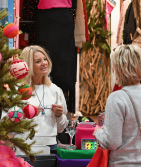 Small business owner blonde woman sells boutique clothes to customer 