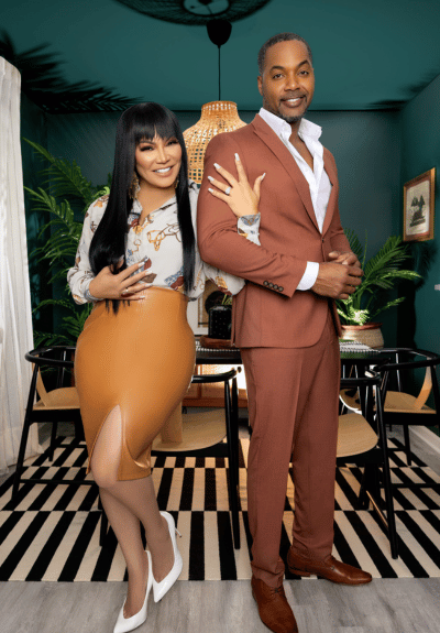 Egypt Sherrod and Mike Jackson standing in front of dark aqua wall on striped carpet