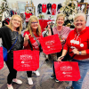 four ladies holding red bags shopping at Greater Cincinnati Holiday Market