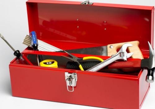 red tool box full of screwdriver, wrench, saw, hammer, and measuring tape