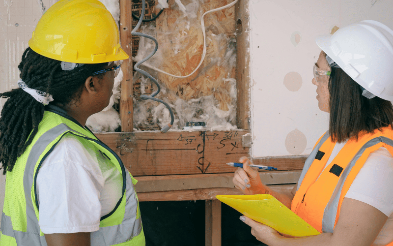 Two female construction worker contractors looking at an electrical job