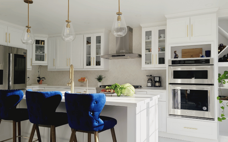 Modern velvet blue chairs in a modern white clean kitchen with hanging gold lights