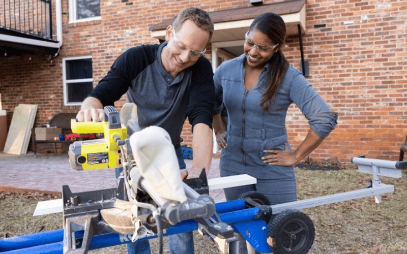 Brian and Mika Kleinschmidt wearing protective eyewear using outdoor saw on home renovation project