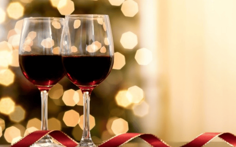 two glasses of red wine with a Christmas tree in the background 