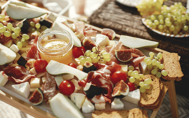charcuterie board with figs, tomatoes, grapes, cheese, and jam