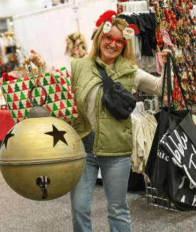 thirty somethign white lady wearing Santa pins in her hair holding giant shopping bags at the Greater Cincinnati Holiday Market