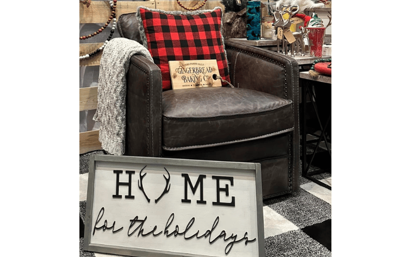 Eight59Boutique festive signs and pillows over brown leather chair in showroom