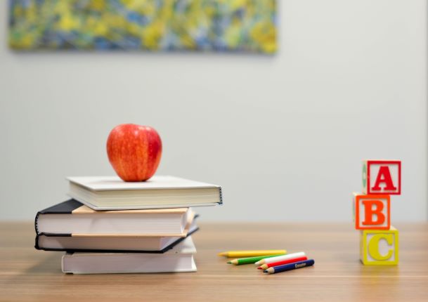 books with an apple on top and letter blocks on a desk