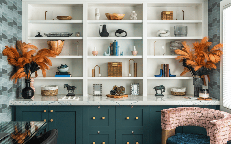 Luxury shelf in dark aqua with brown fake plants and neutral colored art pieces