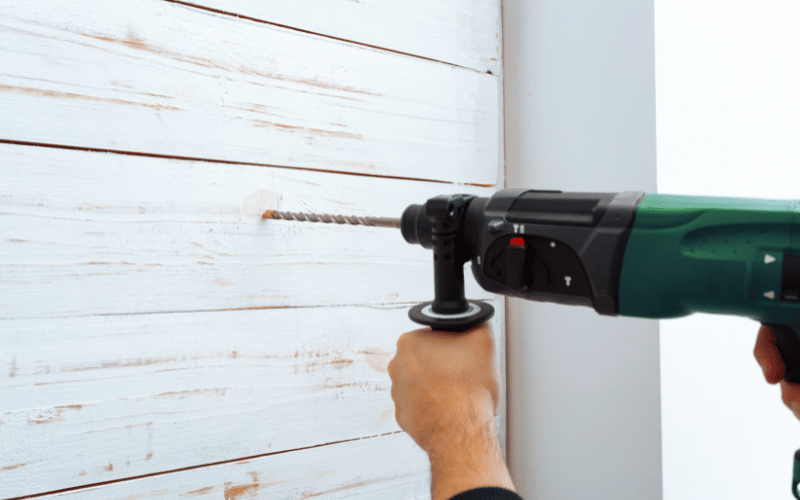 a green drill putting a hole in a wall 