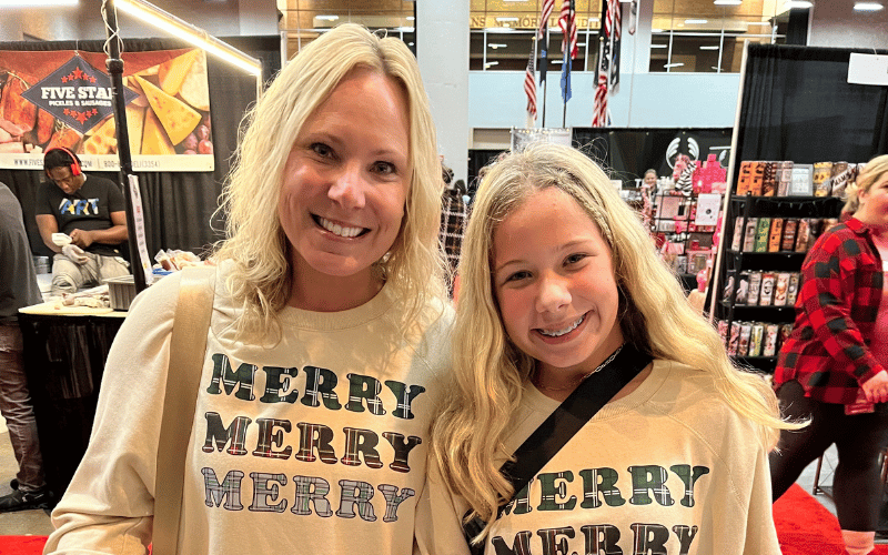 two women smiling wearing Christmas graphic hoodies 