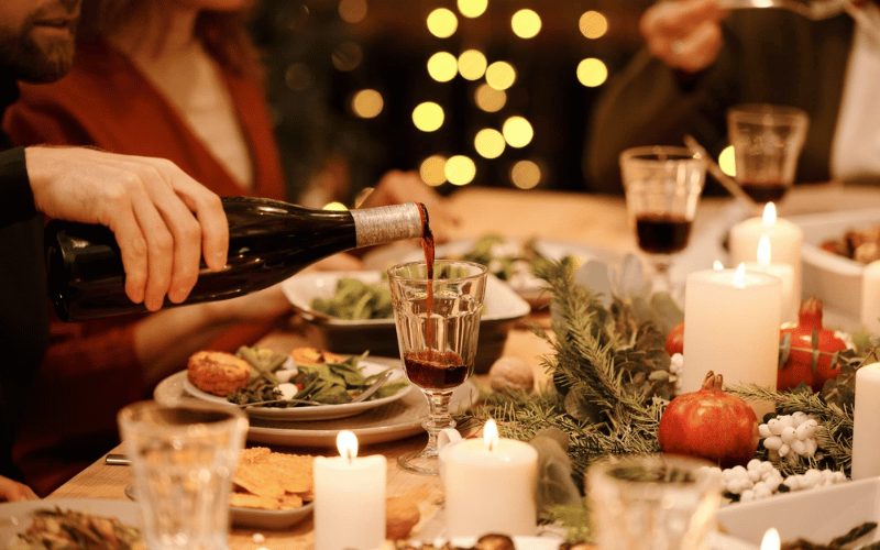 a Christmas dinner table with candles and wine glasses and wine bottles on top 