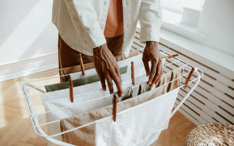 man using an indoor clothing rack to hang wet clothes on