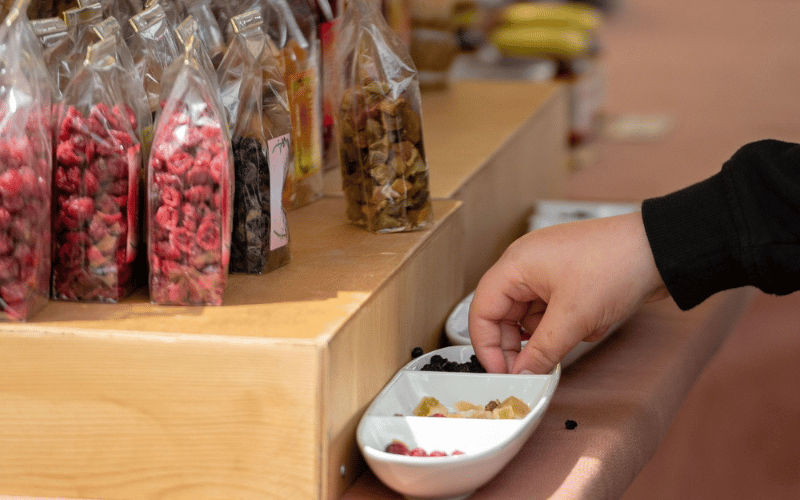 a hand picking out candy from a candy bowl