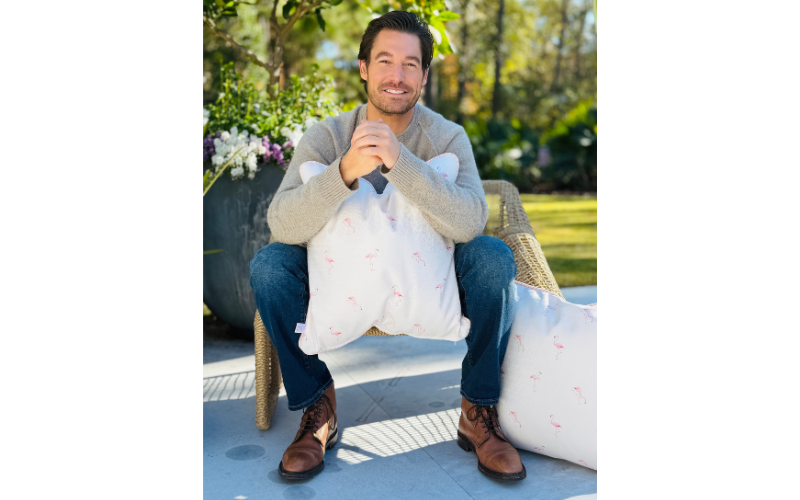 Craig Conover sitting on a chair and holding a pillow 