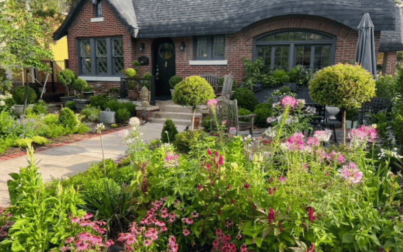 a large garden with pink flowers in front of a house