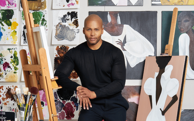 Michael Boyd posing for a photograph in front of an art wall 