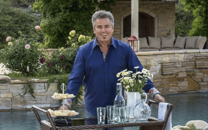 Christopher Knight standing near a small table with food and drinks on top 