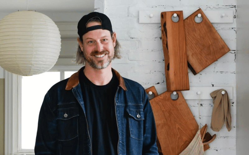 man wearing a denim jacket wearing a baseball cap standing next to a tool wall