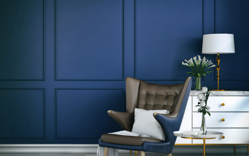 a dark blue painted wall and white furniture