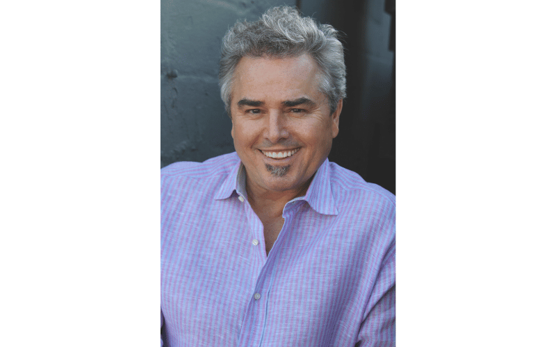 Christopher Knight smiling for a photo wearing a blue shirt 