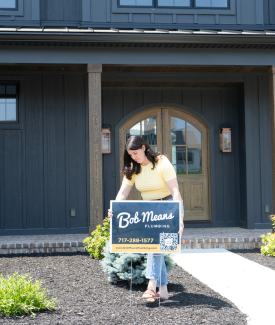 Happy Customer Placing Bob Means Plumbing Sign on Lawn Happy Customer Placing Bob Means Plumbing Sign on Lawn