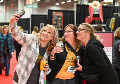 3 girls posing with cocktails taking a selfie at the Omaha Holiday Boutique