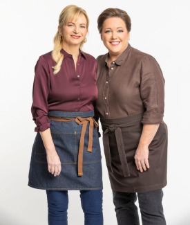 Bridget Lancaster and Julia Collin Davis posing wearing brown and red tops and aprons