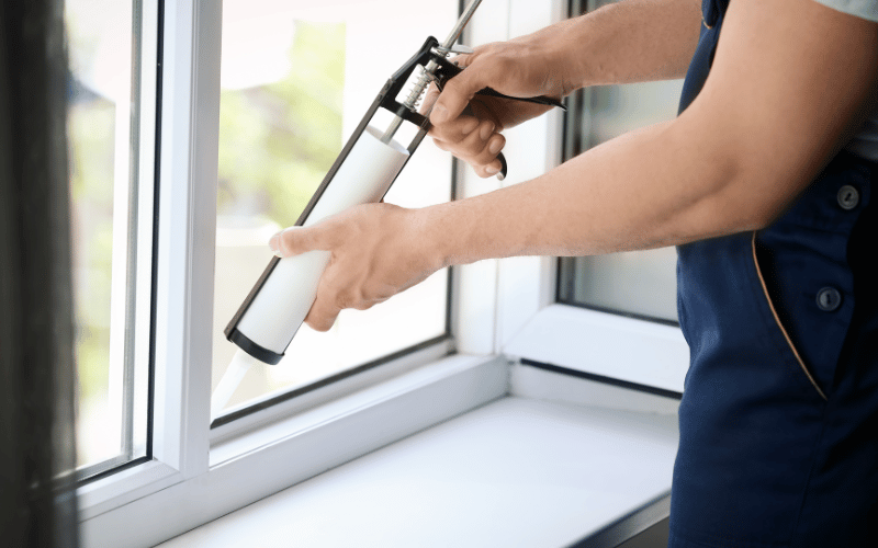 hands holding tool caulking front window