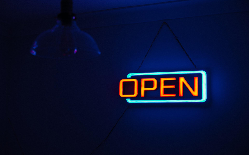 Neon orange and aquamarine open sign over dark blue background