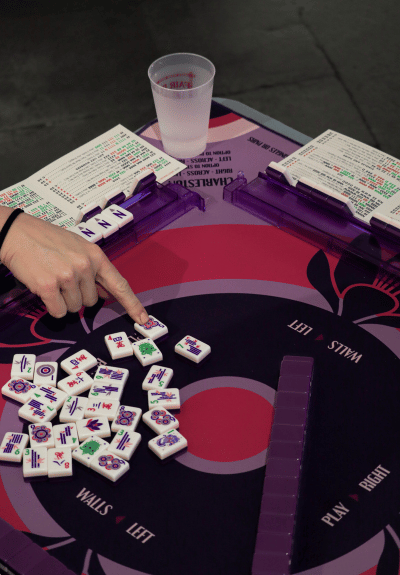 Female hands pointing to Meh Jong Tiles on table black, red and purple table 