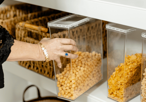 Hand reaching into get cereal out of organized pantry
