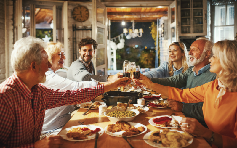 Family sitting around a dinner table sharing a thanksgiving meal and sharing a glass of wine