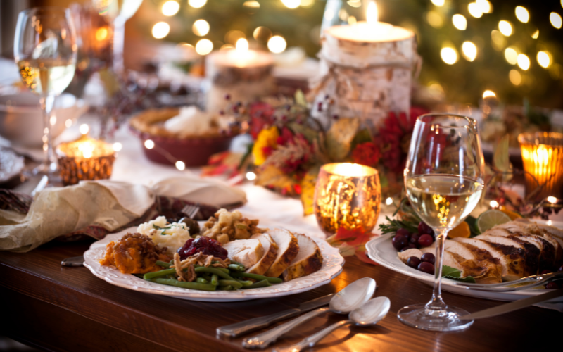 A large dinner table with plates that have sliced turkey, green beans, and cranberry sauce