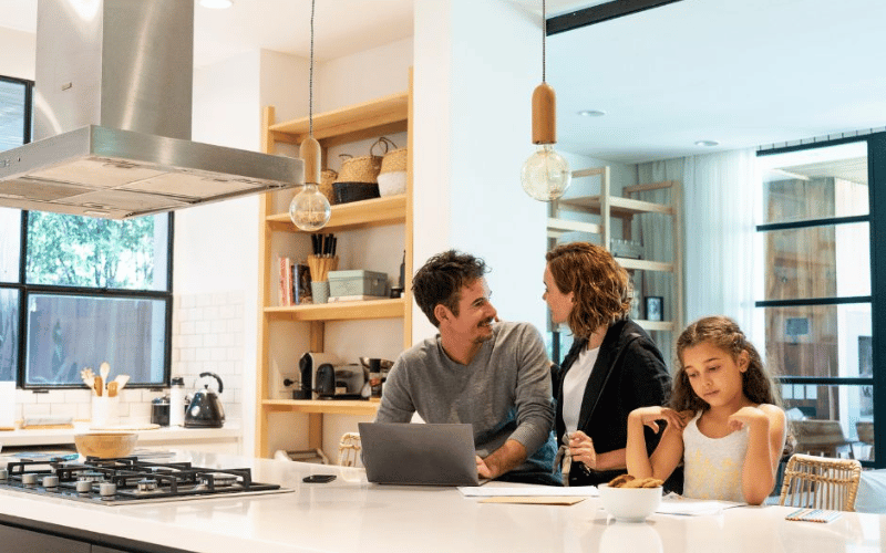 Family sitting together at breakfast bar working smiling in kitchen