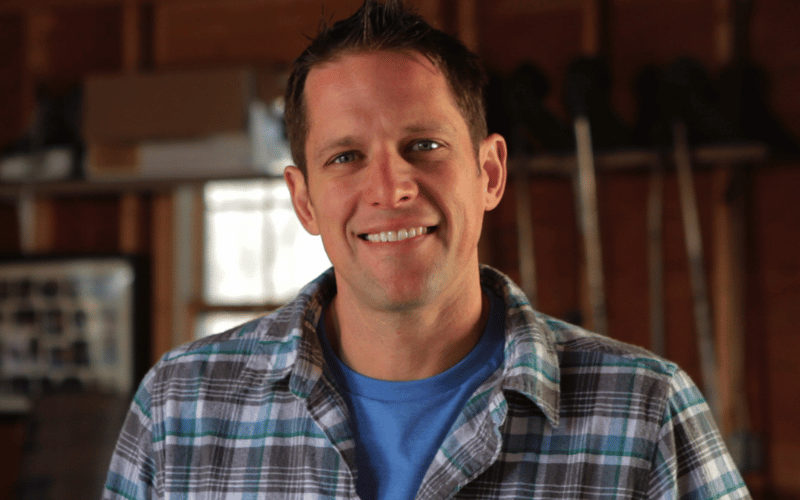 Chris Lambton wearing blue, grey and white plaid shirt smiling at camera headshot