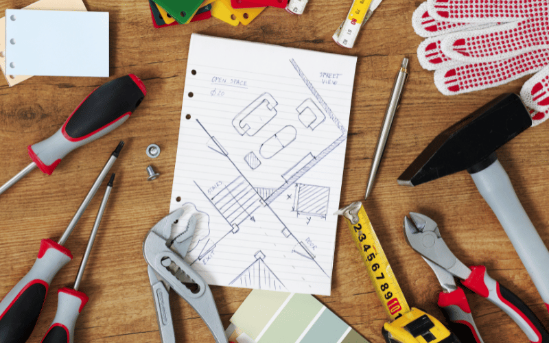 DIY image of makeshift blue prints surrounded by tools on wooden floor