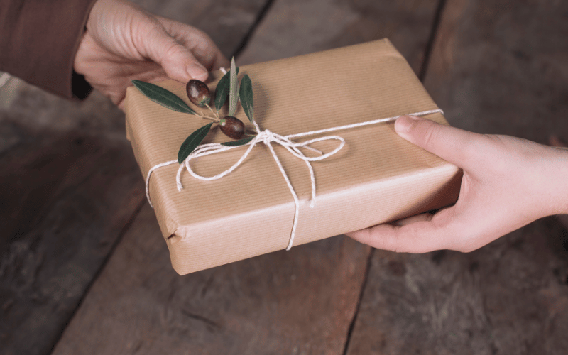 gift giving close up of hands handing each other a beige paper wrapped gift