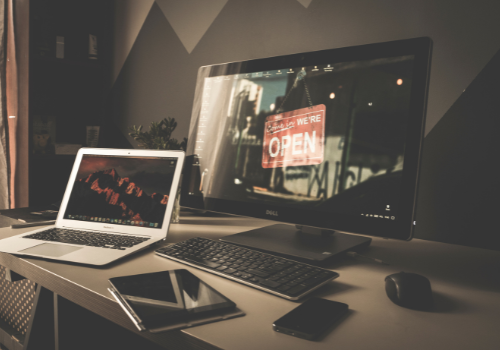 Desk with a laptop, monitor, keyboard and tablet on it.