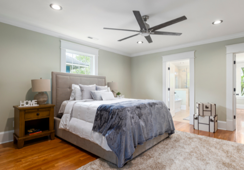 Modern bedroom with dark blue sherpa blanket and ceiling fan above bed